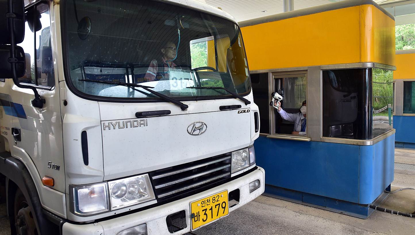 An official (right) checks the body heat of a South Korean truck driver arriving from North Korea's Kaesong Industrial Complex, at the South's CIQ (Customs, Immigration, Quarantine) gate at the inter-Korean transit office in Paju on June 13, 2015.&nb