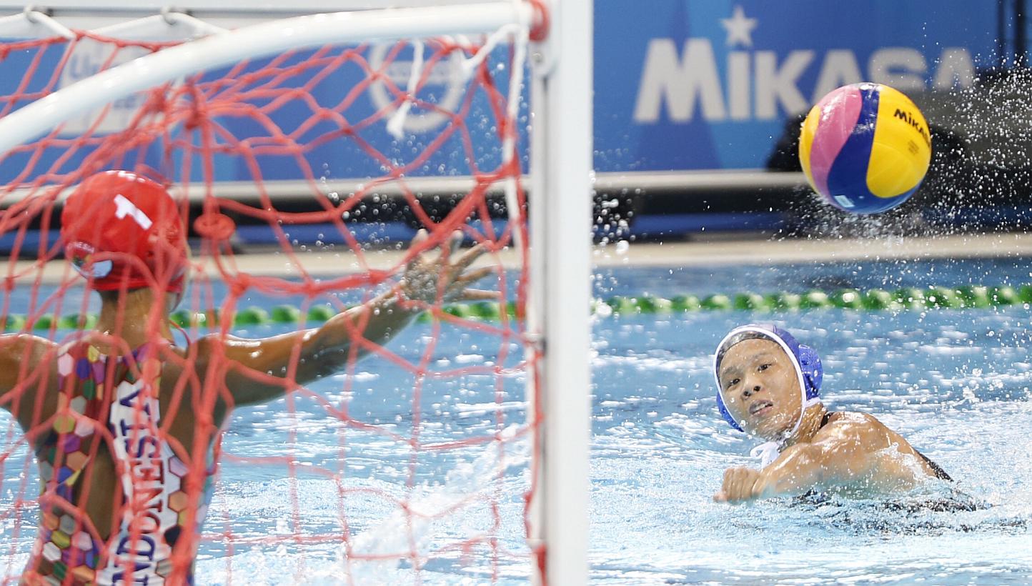 Singapore's Loke En Yuan (right) scores a goal against Indonesia in the women's water polo round robin match 1 during the 28th SEA Games at the OCBC Aquatics Centre on June 10, 2015. -- ST PHOTO: KEVIN LIM