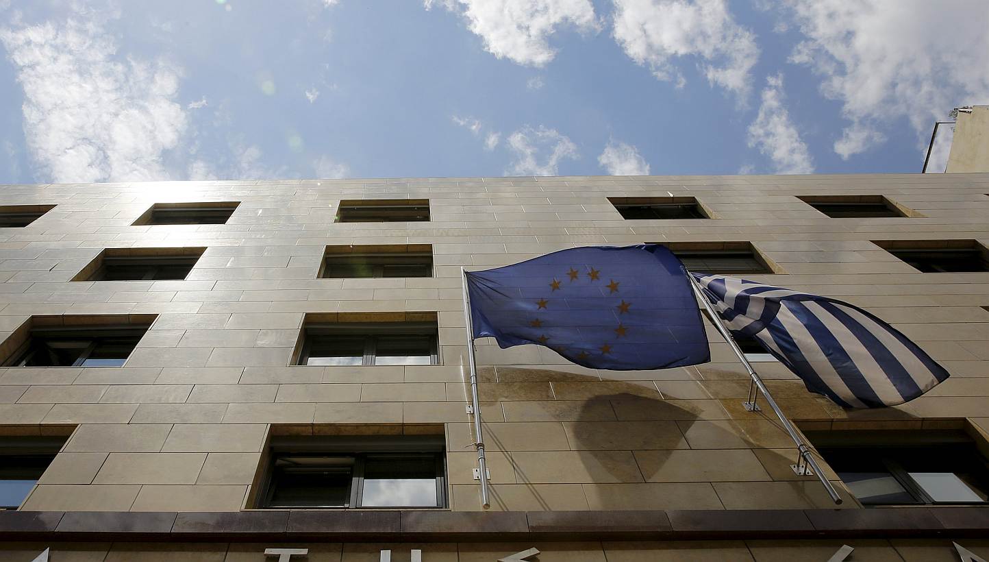 A European Union flag (left) and a Greek national flag flutter at the entrance of the Bank of Greece headquarters in Athens on June 11, 2015.&nbsp;The collapse of talks between Greek ministers and their bailout creditors and a slide in Wall Street le