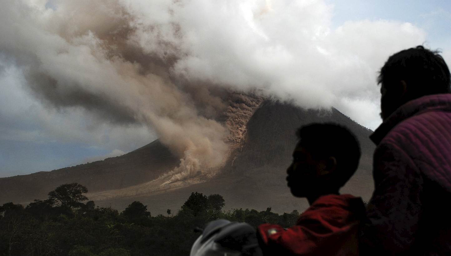 Residents sit on their motorcycle as they watch an eruption at Mount Sinabung, in Namanteran village in Karo Regency, Indonesia's North Sumatra province on June 14, 2015. -- PHOTO: REUTERS