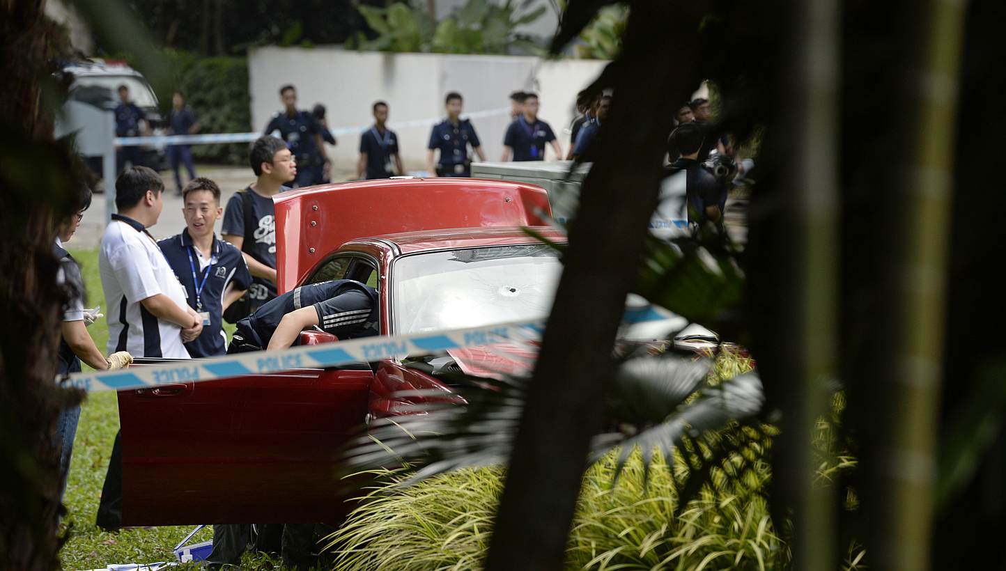 Singapore police officers inspect a red sedan car with a bullet hole on the windscreen which was involved in an early morning shooting incident after it illegally bypassed a police vehicular checkpoint, on May 31, 2015. One of the passengers in