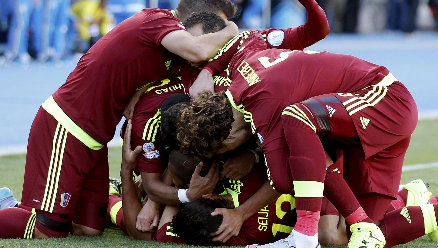 Venezuela players mob teammate Jose Rondon (obscured) as they celebrate his goal against Colombia during their first round Copa America 2015 soccer match at Estadio El Teniente in Rancagua, Chile on Sunday. -- PHOTO: REUTERS