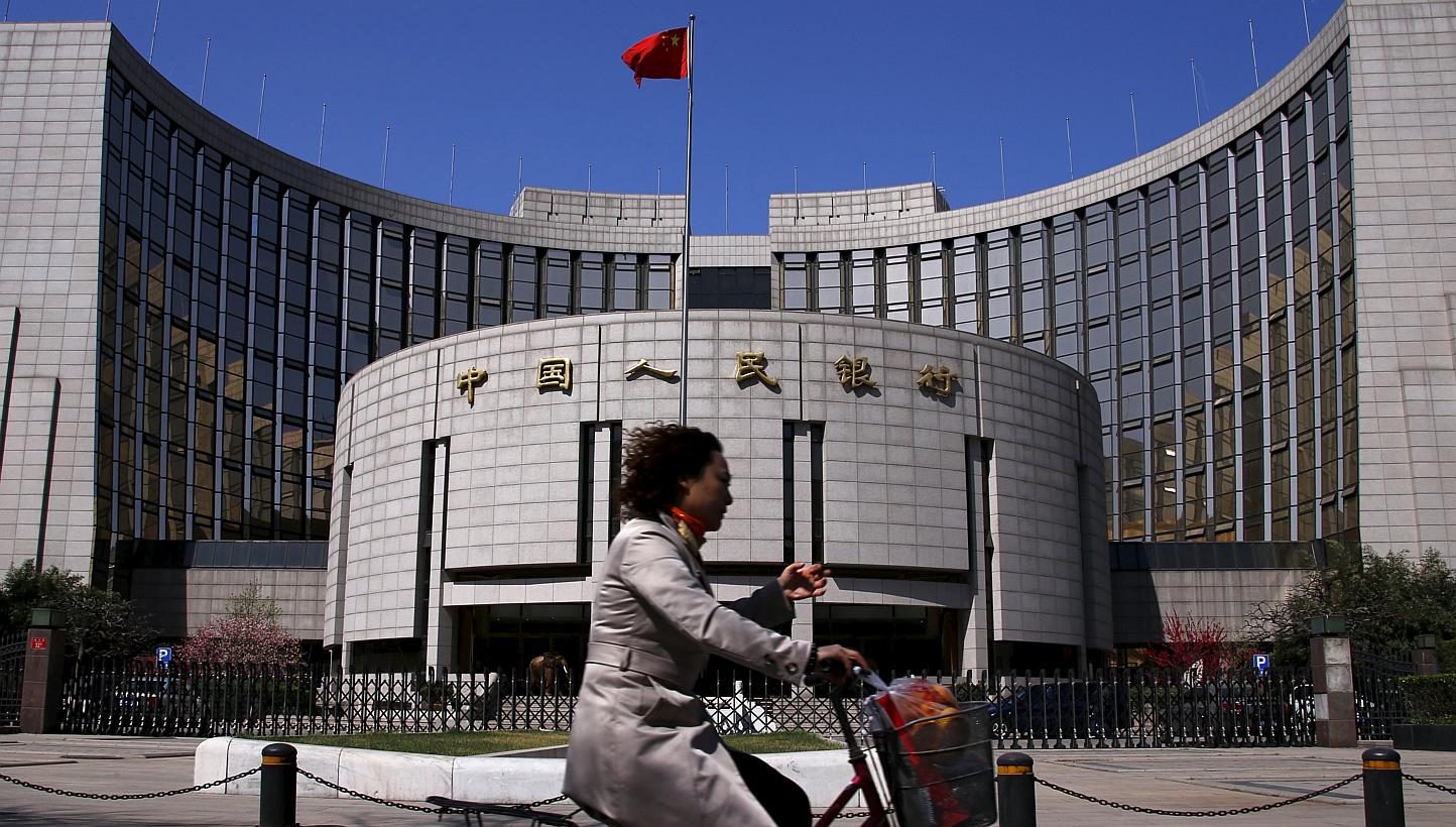 A woman rides past the headquarters of the People's Bank of China in Beijing on April 3, 2014. China will allow private investment funds to trade in the country's interbank debt market for the first time, a central bank document dated June 15 and obt