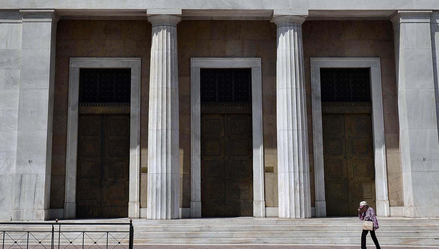A woman walks past Bank of Greece headquarters in central Athens on June 15, 2015. Asian stocks fell as investors awaited an update from the Federal Reserve on US monetary policy and a meeting of euro-area finance ministers with Greece. -- PHOTO: AFP