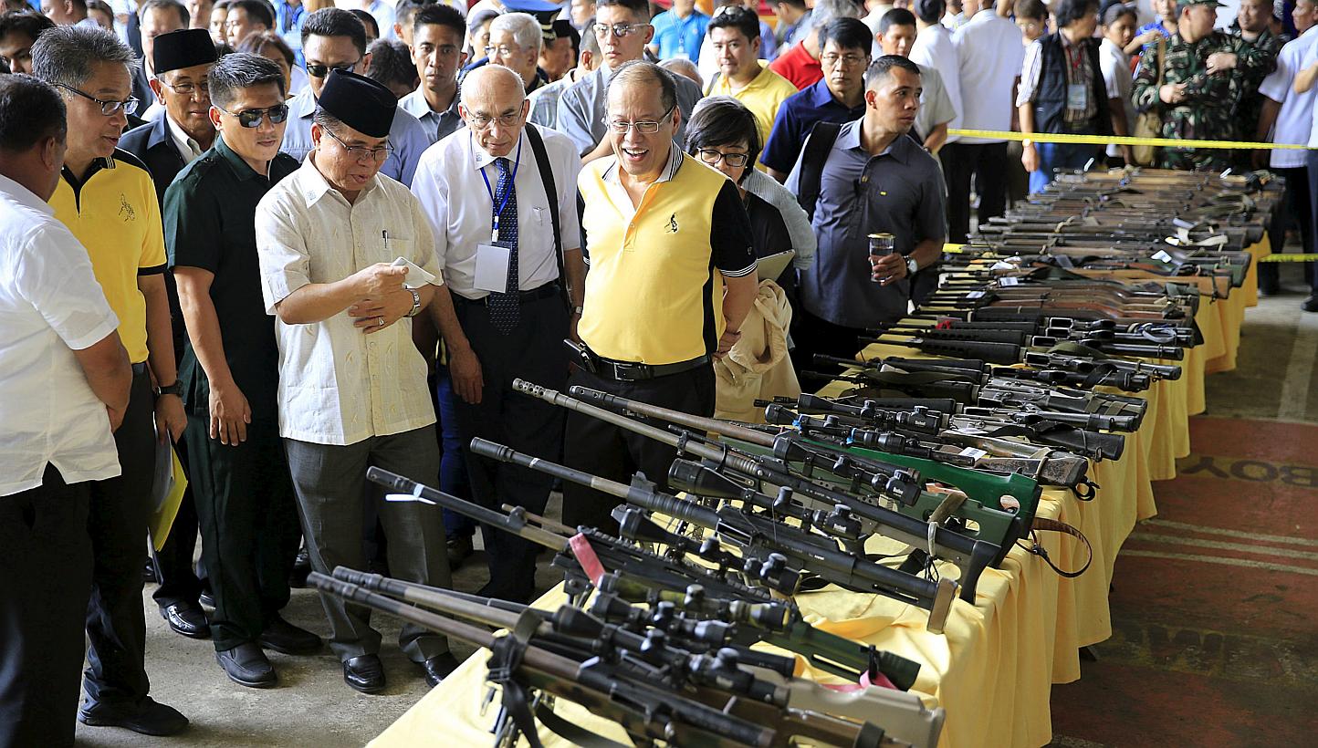 Philippine President Benigno Aquino (front right) and Al-haj Murad Ebrahim (front third right), chairman of the Moro Islamic Liberation Front (MILF), look at weapons during the Ceremonial Turnover of Weapons and Decommissioning of MILF Combatants on 