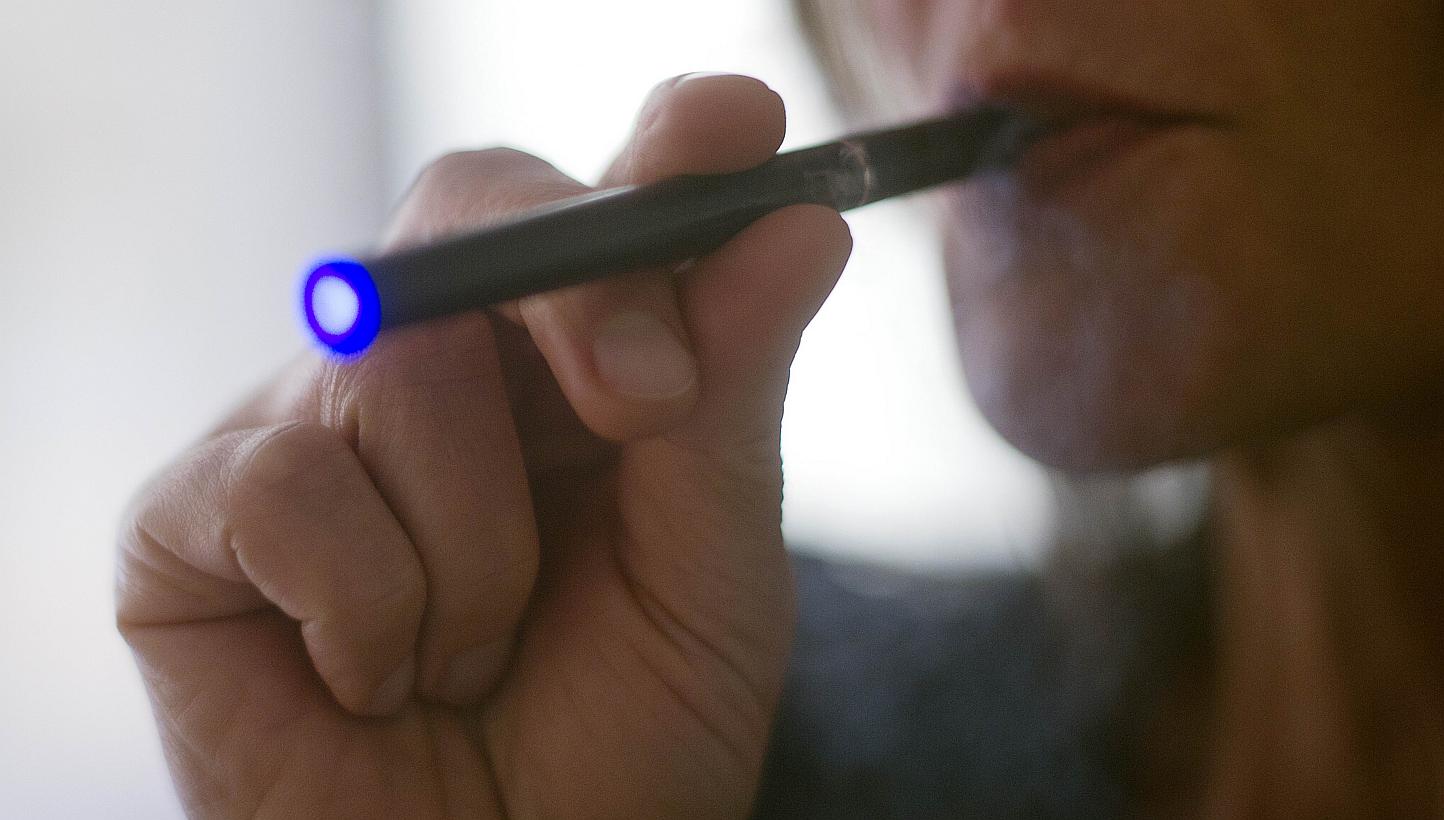 This Sept 25, 2013 file photograph illustration shows a woman smoking an e-cigarette in Washington, DC. The International Civil Aviation Organisation announced Monday a ban on e-cigarettes in checked baggage, following reports they have sparked fires