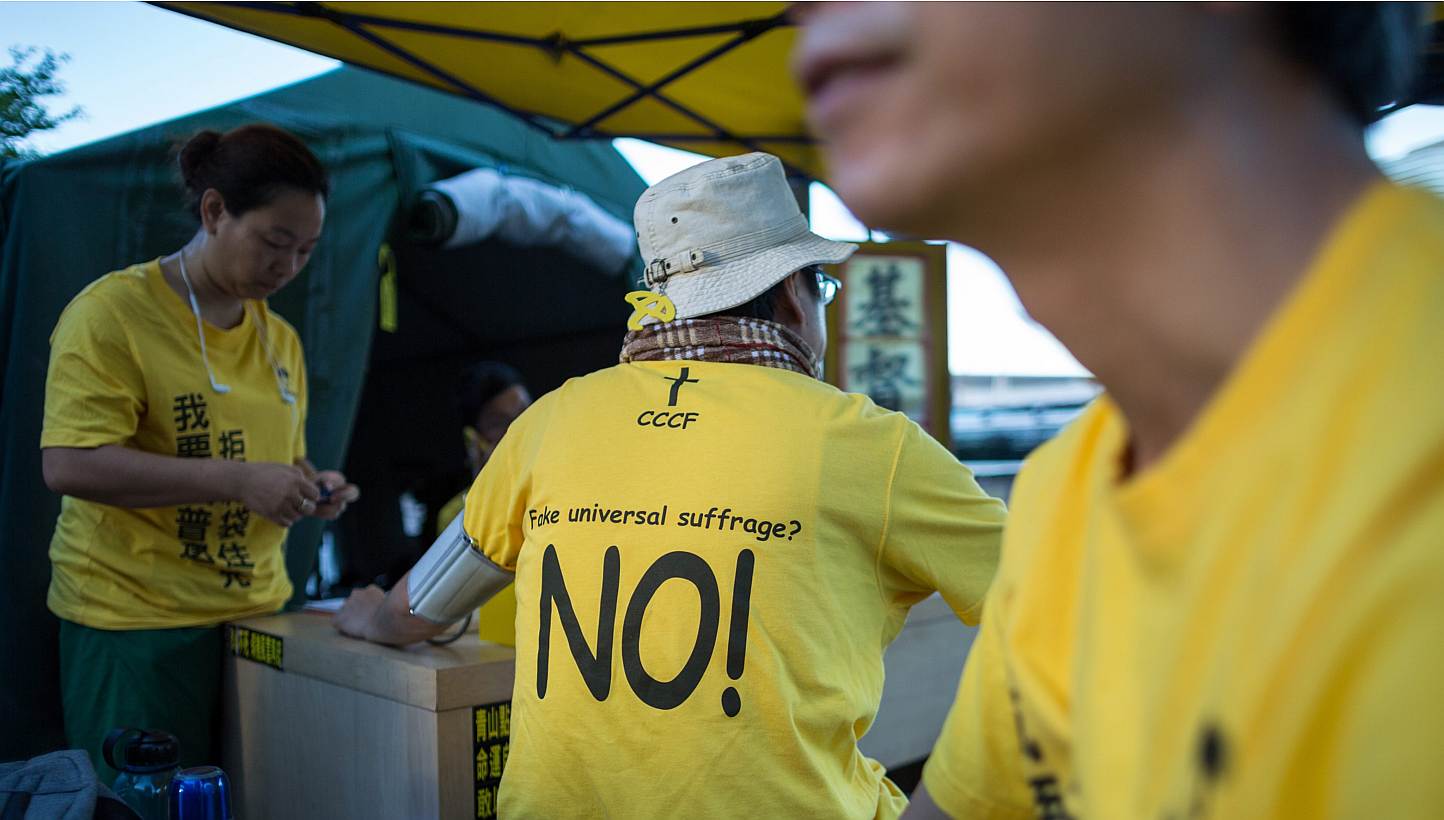 A protester wears a t-shirt against "fake universal suffrage" in a makeshift tent outside the Legislative Council in Hong Kong, China, on June 15, 2015. Hong Kong's Legislative Council (LegCo) will this week debate and vote on a bill on electoral ref