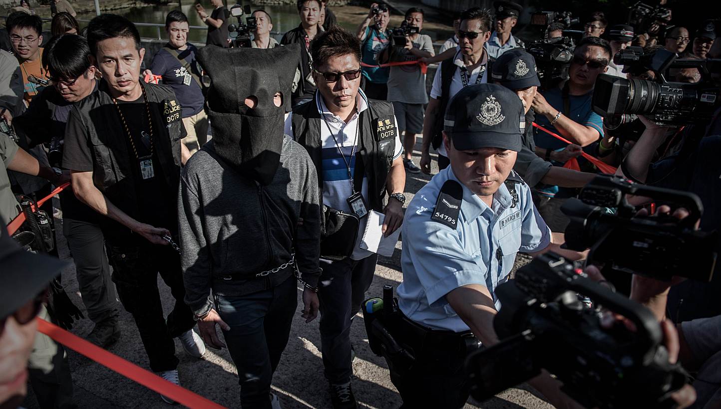 A suspect is escorted by policemen during a crime reconstruction in the east-coast district of Sai Kung in Hong Kong on June 16, 2015 a day after suspected explosives were seized at an abandoned television studio. China on Tuesday warned against