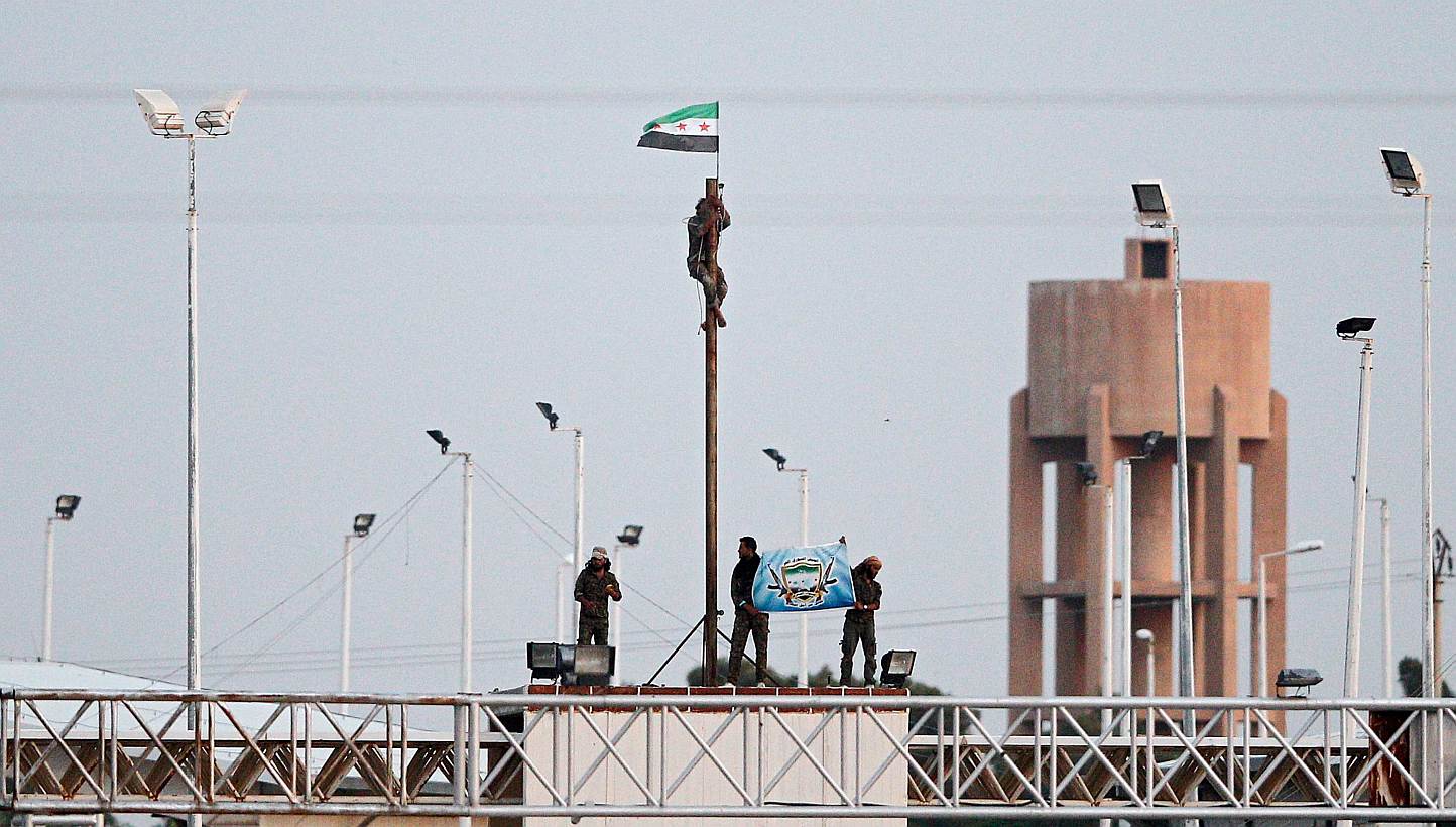 A picture taken from the Turkish side of the border between Turkey and Syria shows members of Free Syrian Army hoisting a flag near the Syrian-Turkish border line in Akcakale, Sanliurfa province, south-eastern Turkey on June 16, 2015. -- PHOTO: EPA