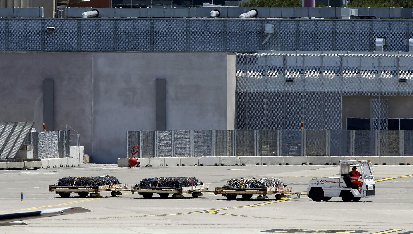An airport vehicle pulls three cargo platforms with coffins on the tarmac at the Marseille Provence Airport in Marignane, France on Monday as Lufthansa prepares to transport coffins with the remains of 30 victims of the Germanwings Airbus A320 crash 