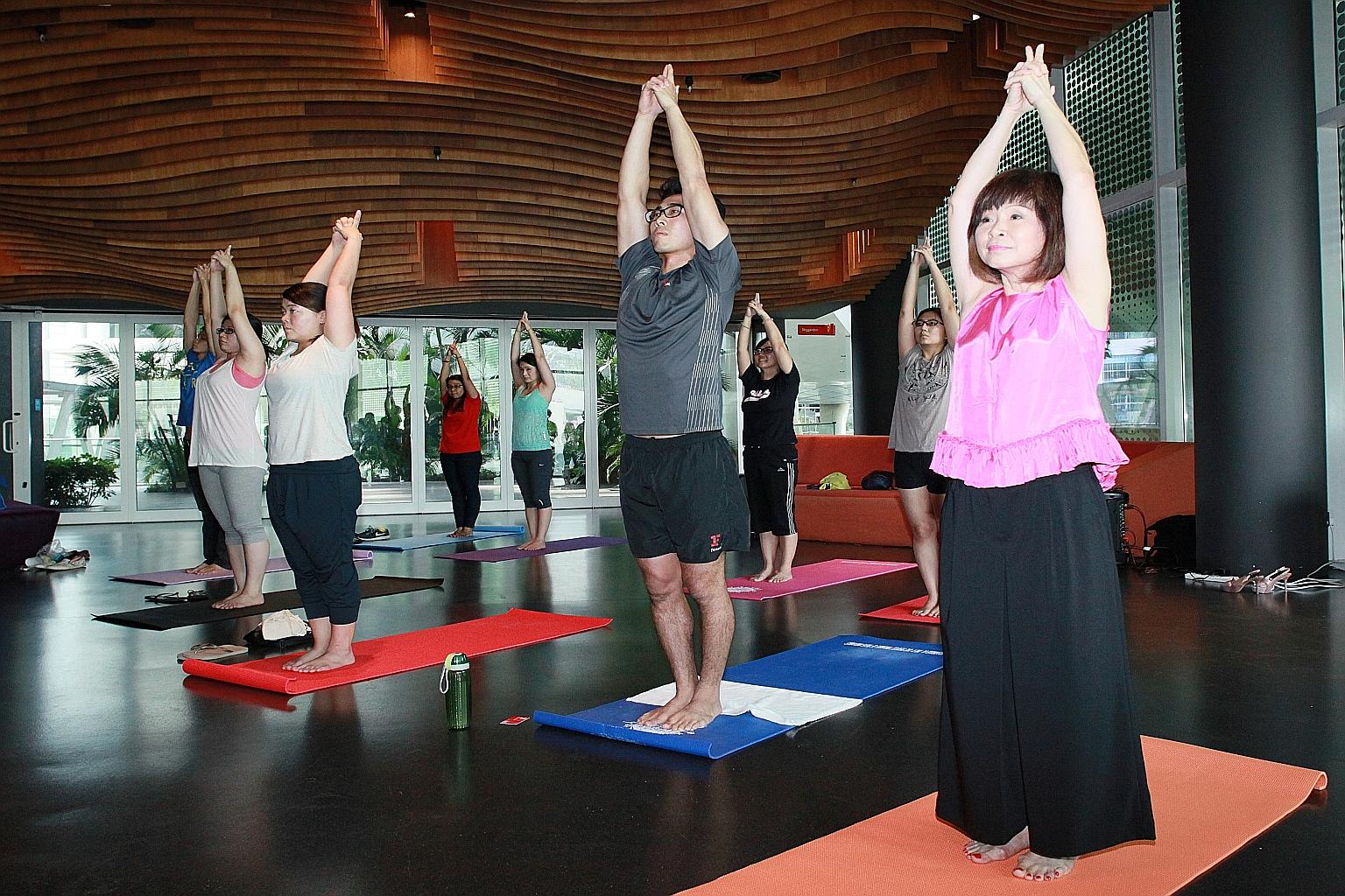 Dr Amy Khor (right) joining a lunchtime yoga class for people working at one-north yesterday. A national committee chaired by Dr Khor is overseeing initiatives to reach at least 120,000 workers.