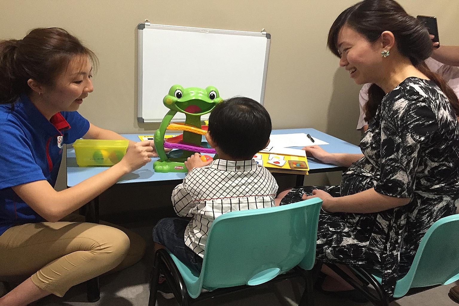 Four-year-old Koo Wen Rui working with his therapist at Thye Hua Kwan Moral Charities' new centre for special needs children yesterday, as Marine Parade GRC MP Tin Pei Ling observes.