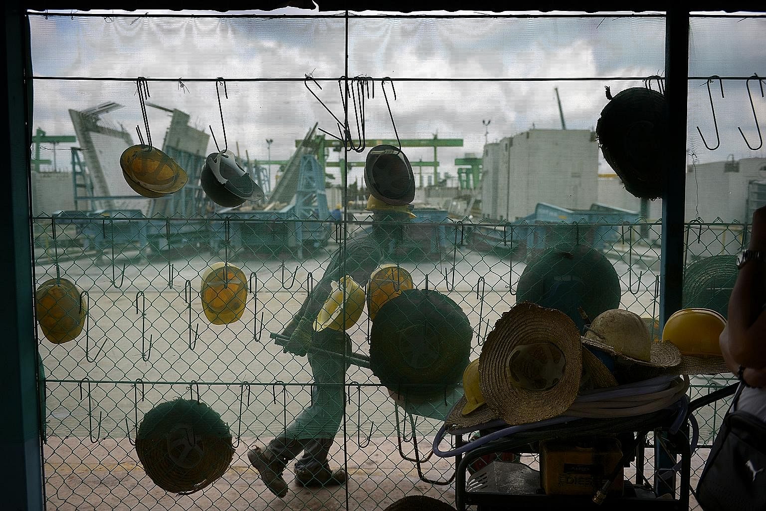 Workers’ safety helmets hanging outside the canteen in the Sunway Concrete precast plant in Tampines. An army of workers work almost daily to churn out tonnes of precast building components for construction sites islandwide.