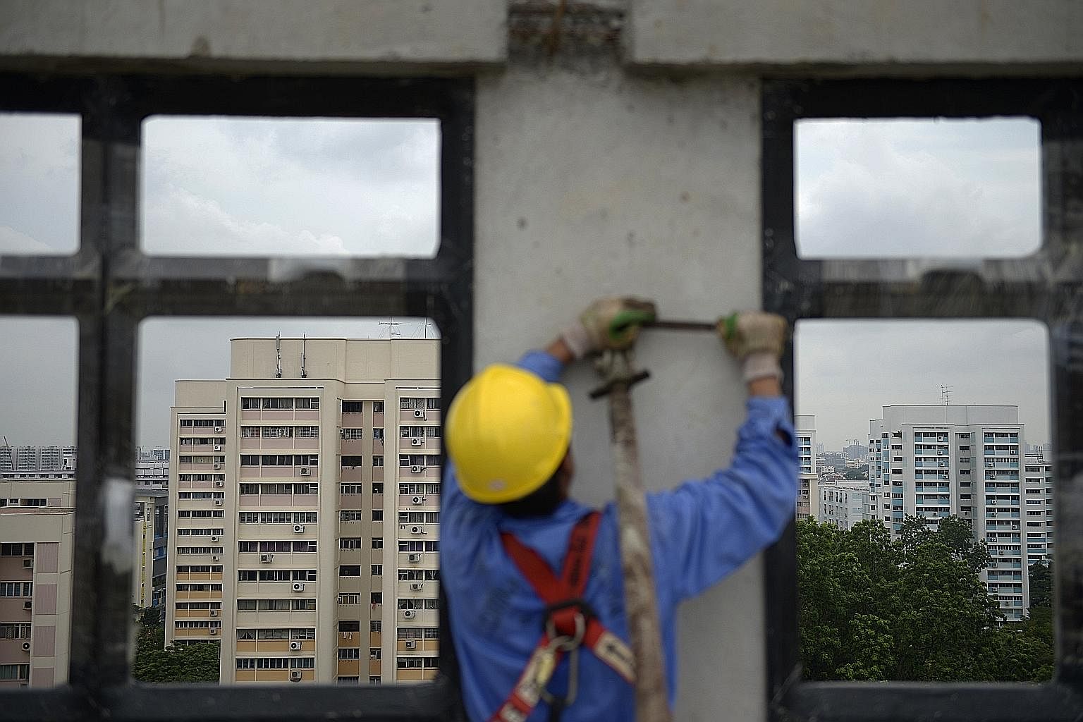 A worker tightening a brace bolted to a facade that had just been lifted into position in a Hougang Crimson block. The brace stays on until the adjoining walls and beams are put in place.