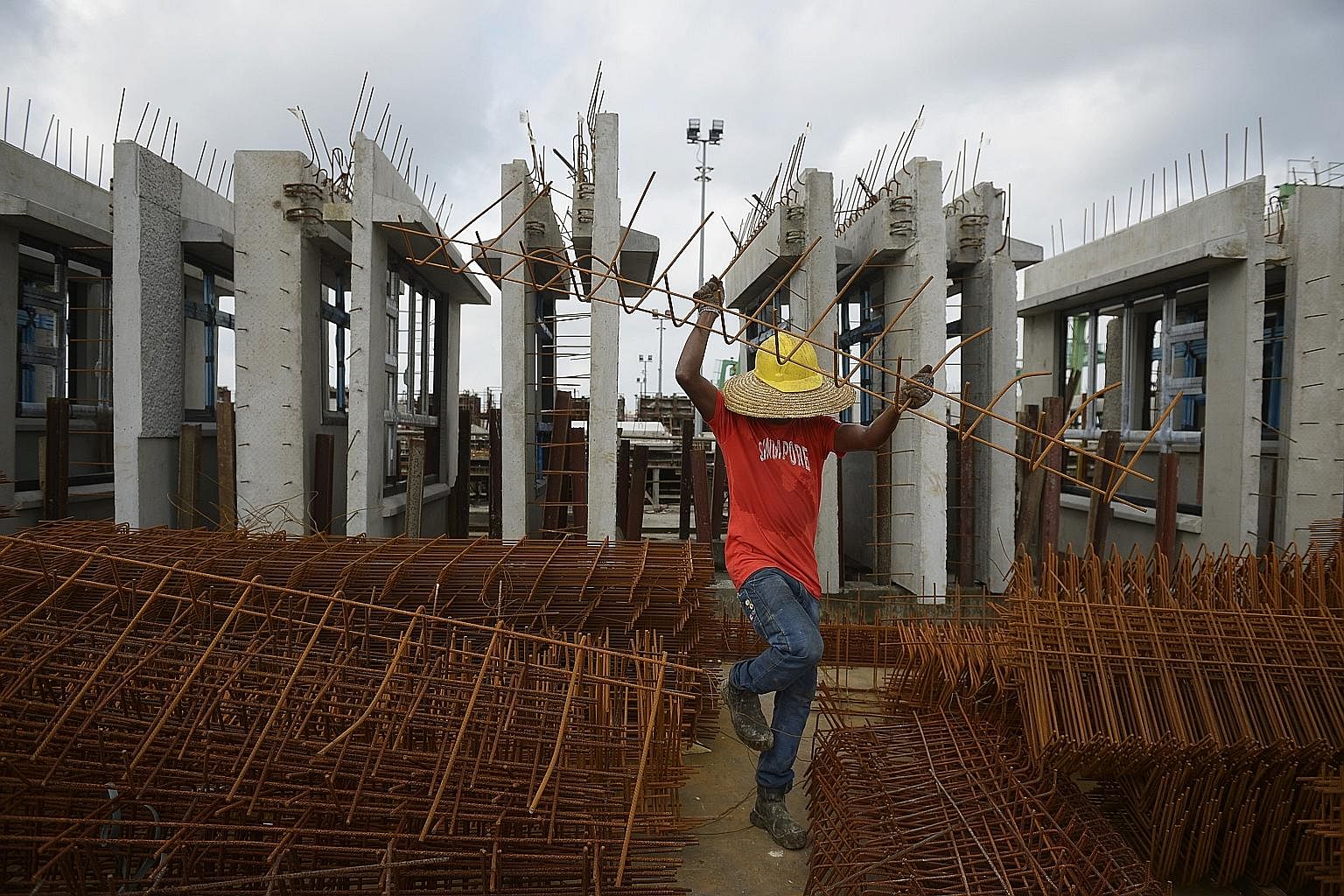 A worker sorting out reinforcing steel bars, known as “rebars”. In the background are HDB facades that are waiting to be delivered to the worksite.