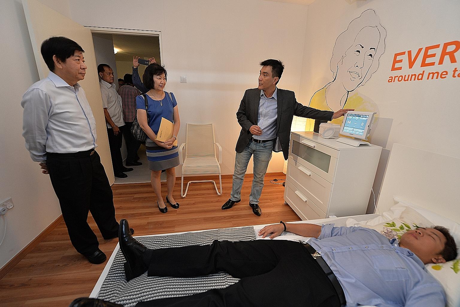 National Development Minister Khaw Boon Wan (left) and HDB CEO Cheong Koon Hean watching a demonstration of a device that can monitor an elderly resident in bed.