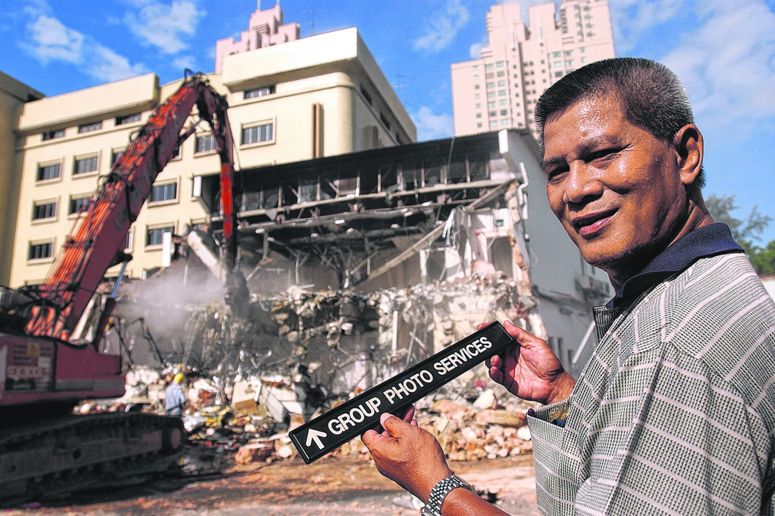 Demolition of the Times House building begins in 2004 to make way for redevelopment, as ex-ST TV cameraman Shahriya Yahaya holds the name plate of the department where he used to work. (Below) Times House staff gather for a group photo before bulldoz
