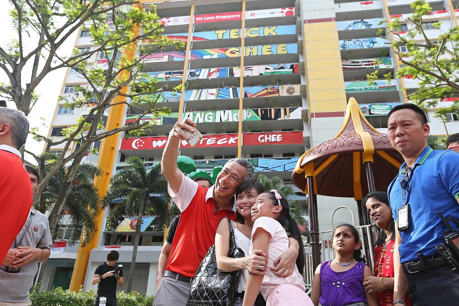PM Lee Hsien Loong taking a wefie with residents in his Teck Ghee ward. He added the finishing touches to a canvas painting used to complete an art facade (background) on one of the HDB blocks.