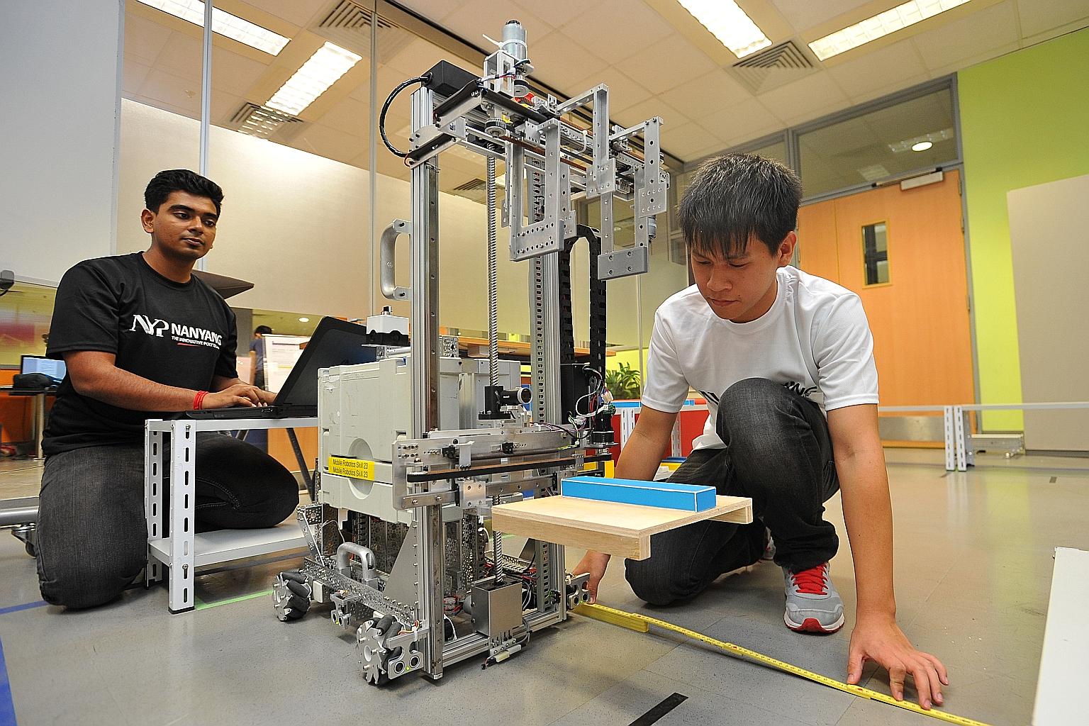 Nanyang Polytechnic graduates Dinesh Mangalanathadurai (left), 19, and Lin Yong Qiang, 22, working on their robot at Nanyang Polytechnic. They will be taking part in the Mobile Robotics category in the WorldSkills competition in Brazil next month. Th