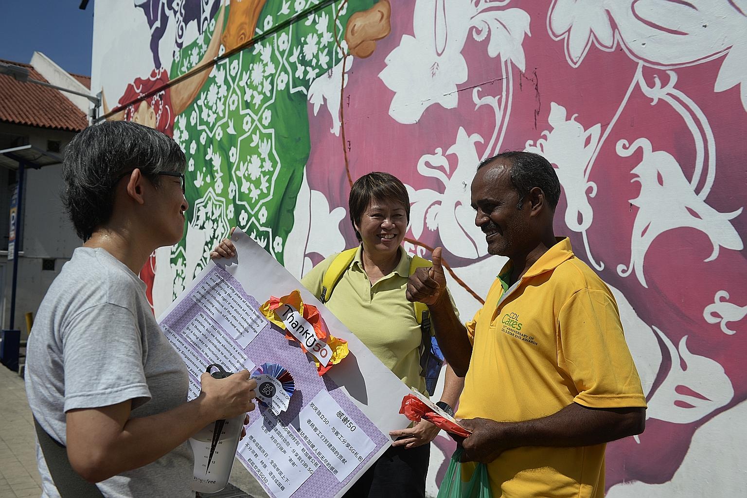 Mr Yap Ching Wi, 47, and Ms Millie Phuah, 54, giving a ThankU50 goodie bag to 39-year-old construction worker Jaganathan Velmurugan, who has worked here for about eight years.