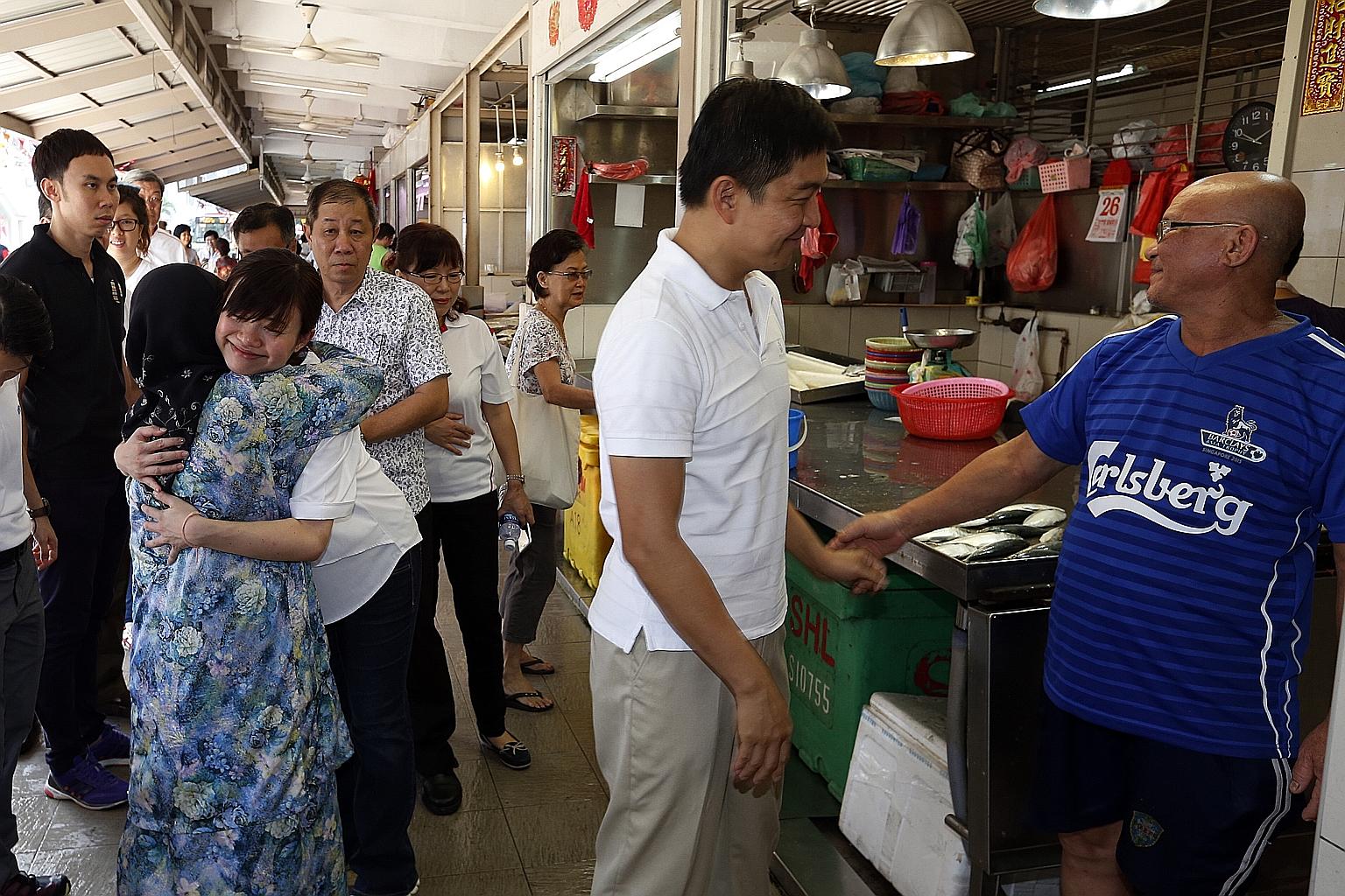Ms Tin Pei Ling (white top) being hugged by MacPherson resident, Madam Fatimah Buang, 75, during her visit to a market yesterday.