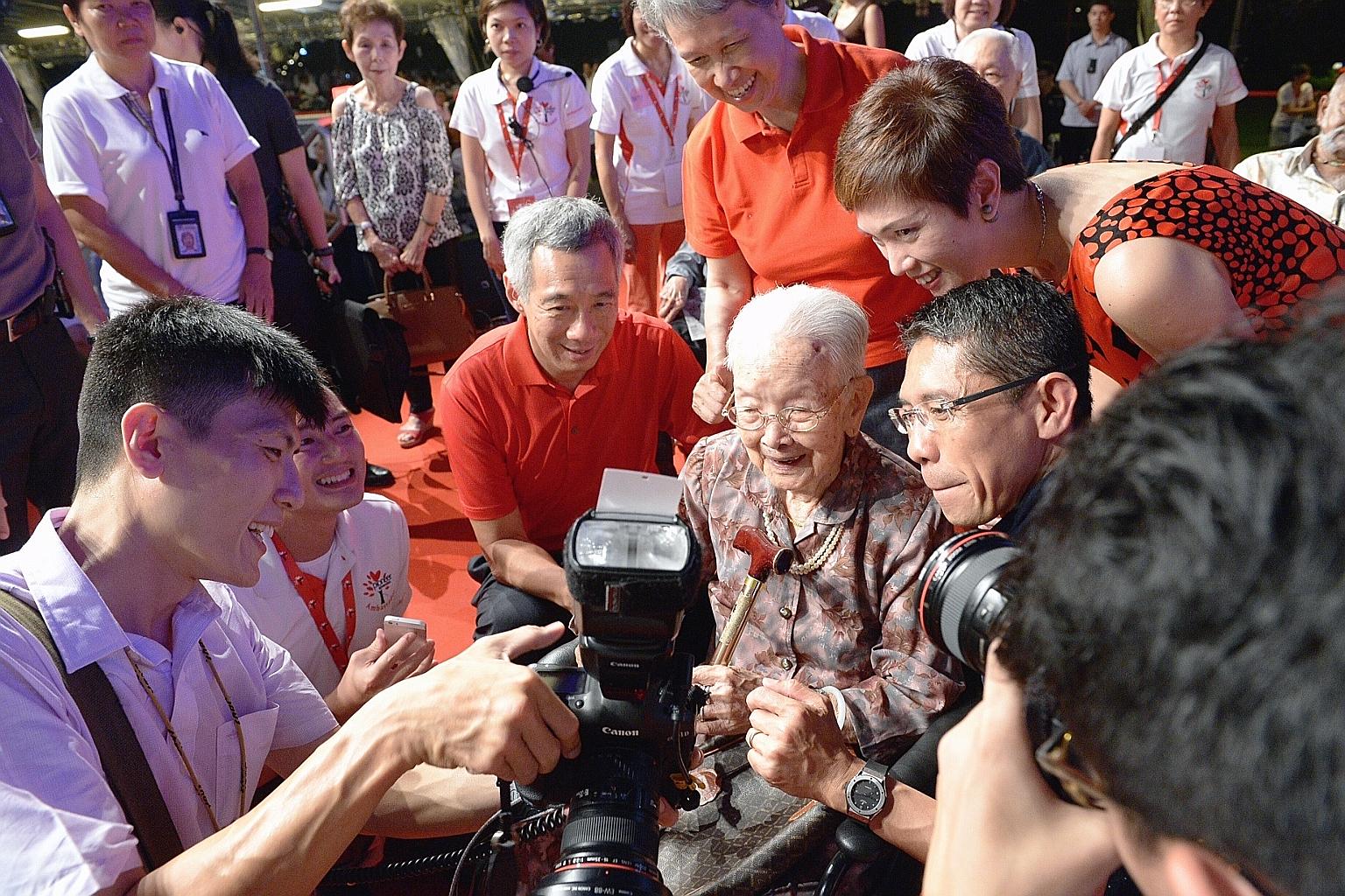 PM Lee Hsien Loong with Madam Lim Beck, 108, looking at a photograph taken of her moments earlier. They are both seen here with PM Lee's wife, Madam Ho Ching (in red T-shirt), Senior Minister of State for Finance and Transport Josephine Teo (far righ