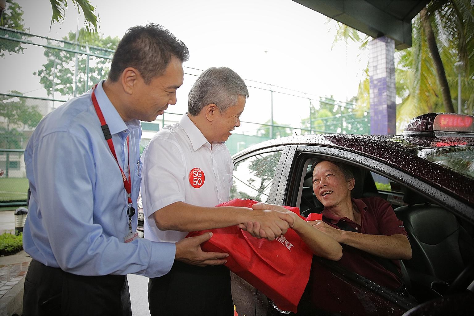 Mr Lim Choon Seng, 67, receiving the SG50 goodie bag from Mr Ang Hin Kee (centre), the executive adviser of the National Taxi Association, and Mr Tony Heng, general manager of SMRT Taxis.