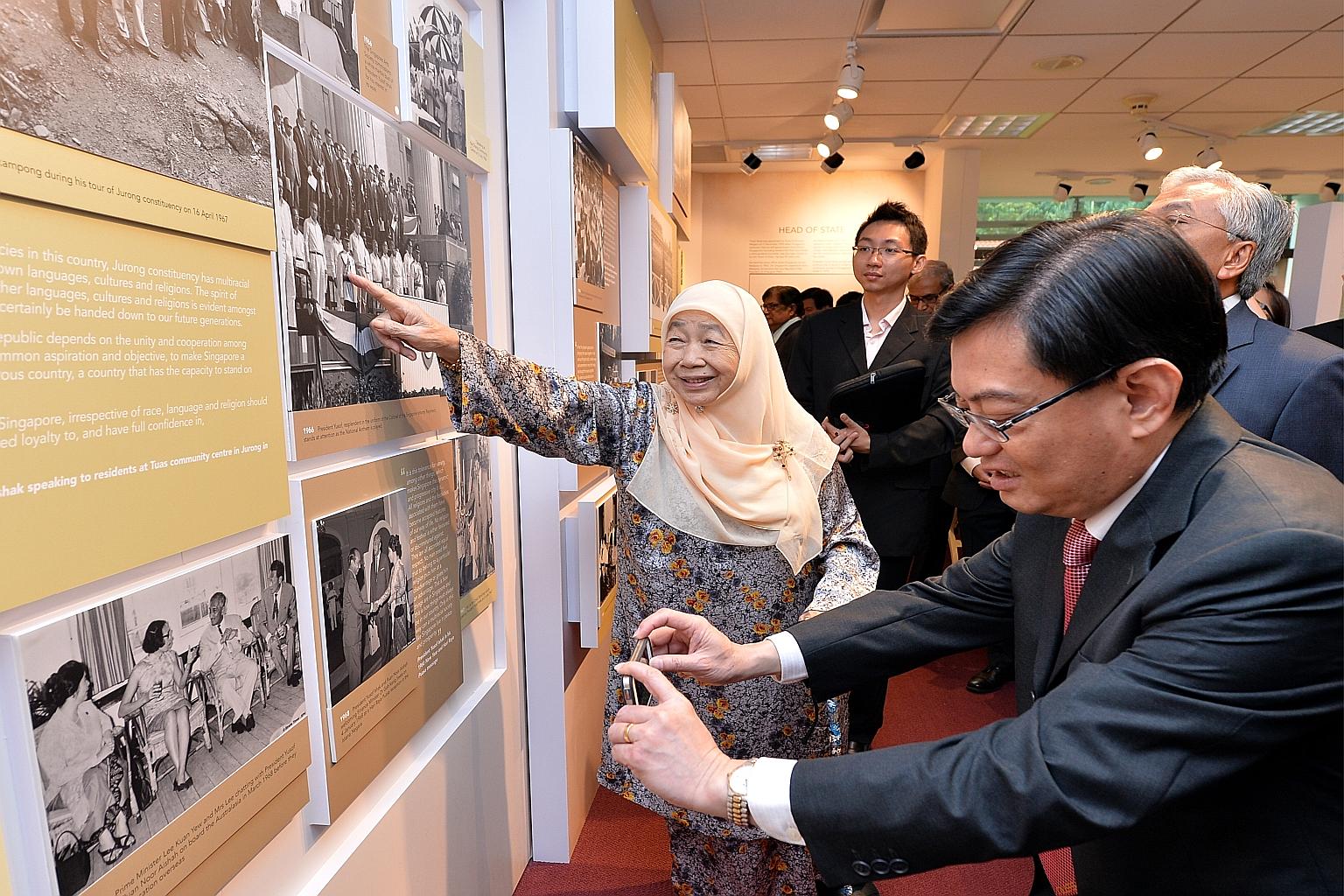 Mr Heng Swee Keat taking a photo of a panel at an exhibition on Mr Yusof Ishak's life at the Iseas library as Madam Noor Aishah, Mr Yusof's wife, points to a 1966 picture of him in ceremonial uniform. The think-tank was renamed in Mr Yusof's honour y