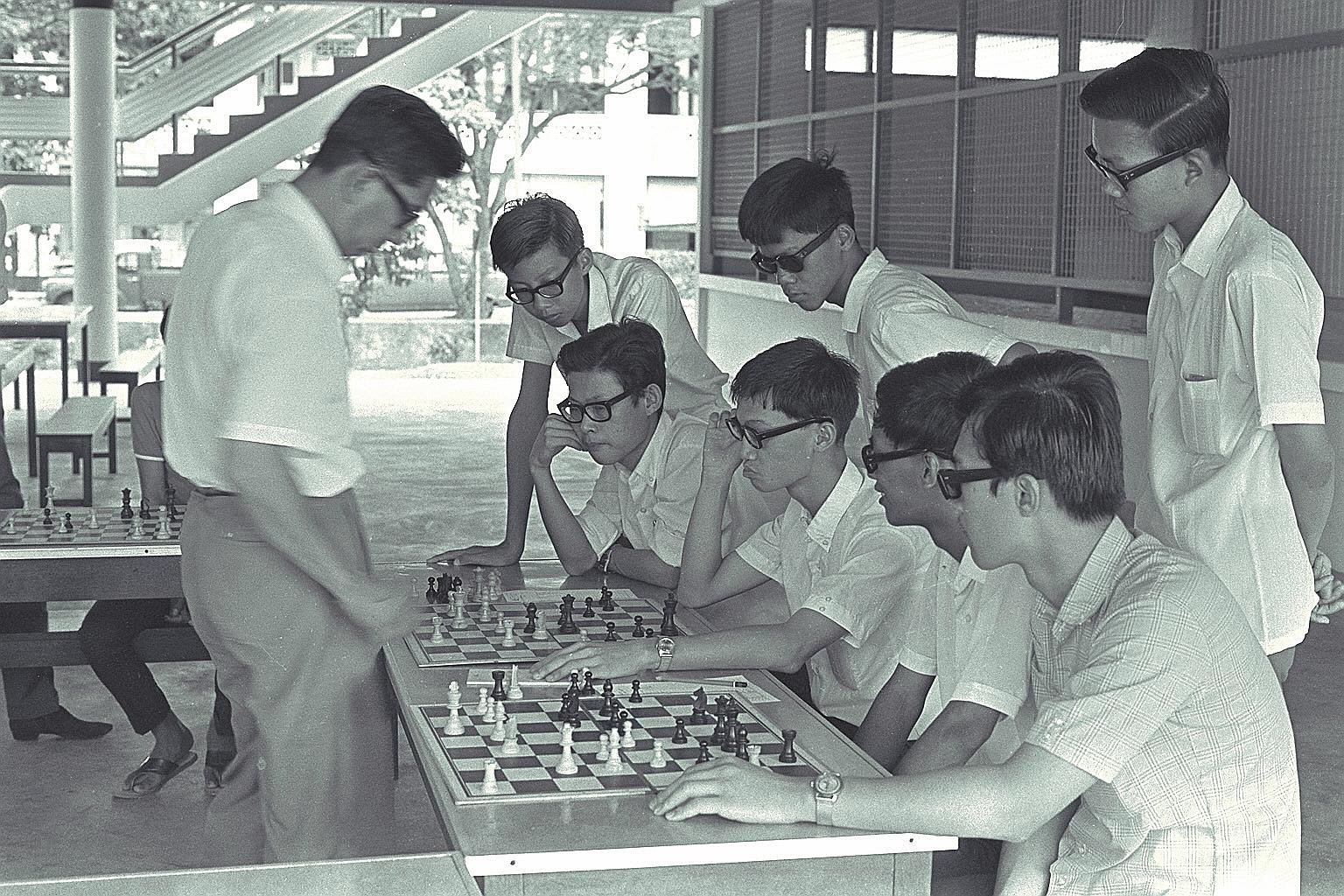 Professor Lim Kok Ann (left) pitted against more than 20 schoolboys in a chess game at the Tanjong Katong Technical School. Last in a series of displays for junior members of the Singapore Chess Olympiad, it was to raise funds to send a team to the n