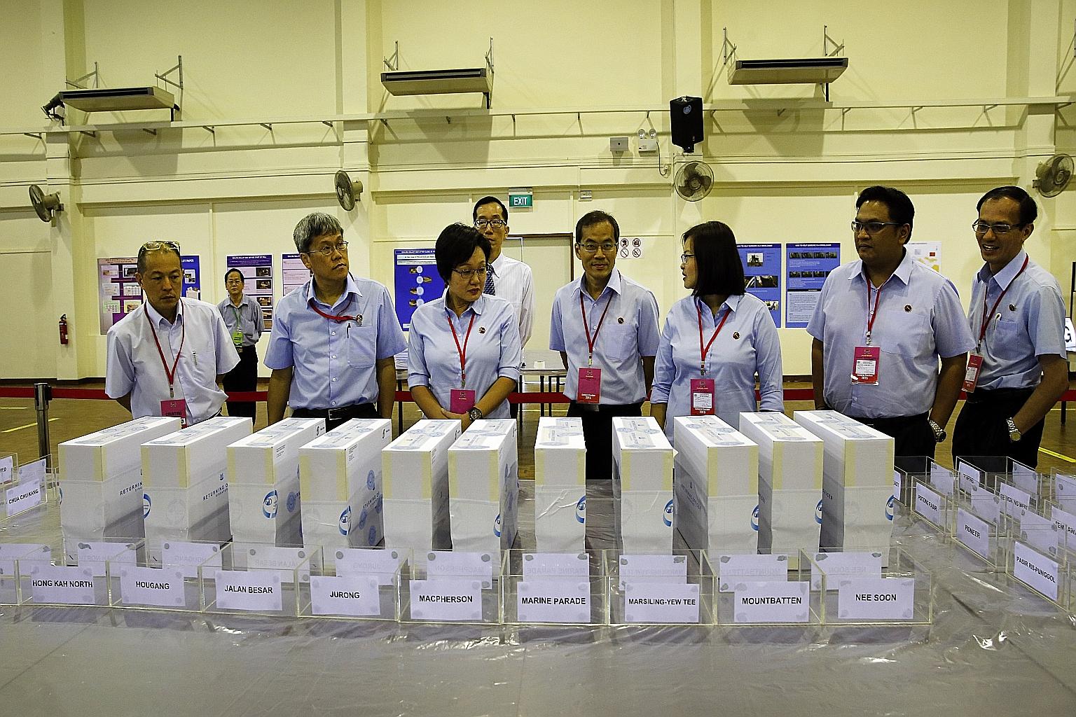 Returning Officer Ng Wai Choong (behind, wearing tie) looking on as the Workers' Party's (from right) Mr Yee Jenn Jong, Mr Redzwan Hafidz Abdul Razak, Ms Lee Li Lian, Mr Dennis Tan, party chairman Sylvia Lim and Mr Png Eng Huat observed the counting 