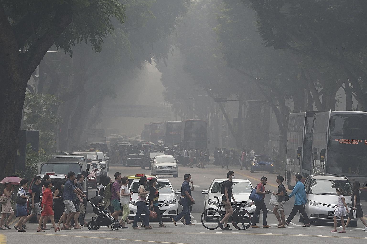 The Orchard Road shopping strip view obscured by haze at 4pm yesterday. Many shoppers kept their masks on as they walked in and out of malls as the air quality deteriorated.