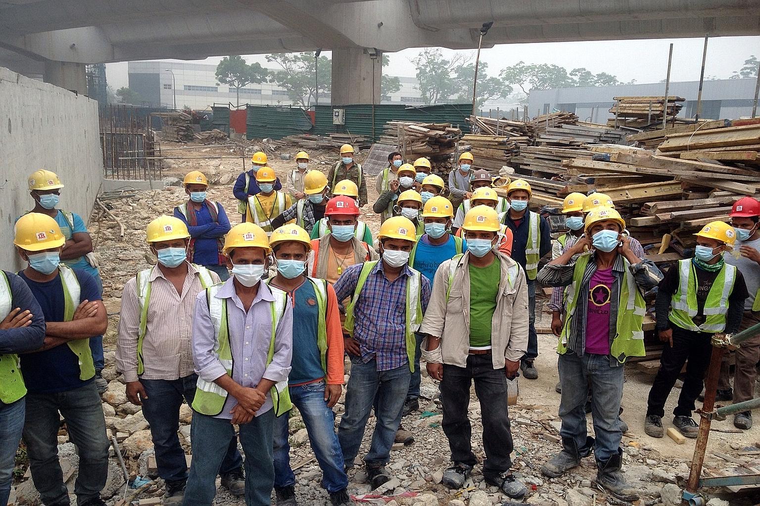 Workers at an MRT construction site in Pioneer Road wearing masks yesterday morning. Their employer, Chong Brothers General Contractor, later replaced their surgical masks with N95 masks, which offer better protection from the haze. The workers have 