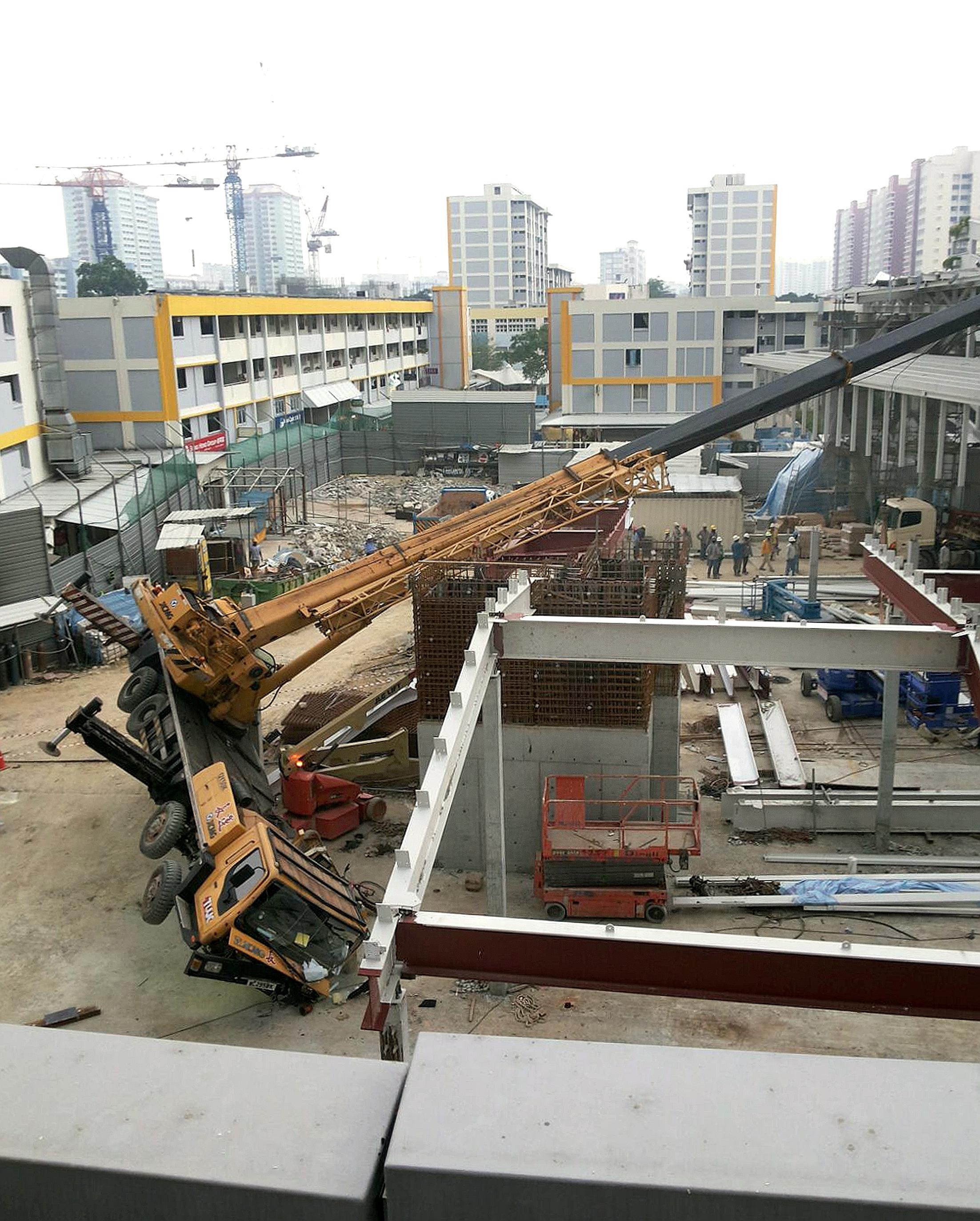 A crane at a hawker centre being demolished in New Upper Changi Road toppled on its side at about 3pm yesterday. No one was hurt in the incident, which took place near the Bedok MRT station. A Straits Times reader sent this picture of the scene. Resp