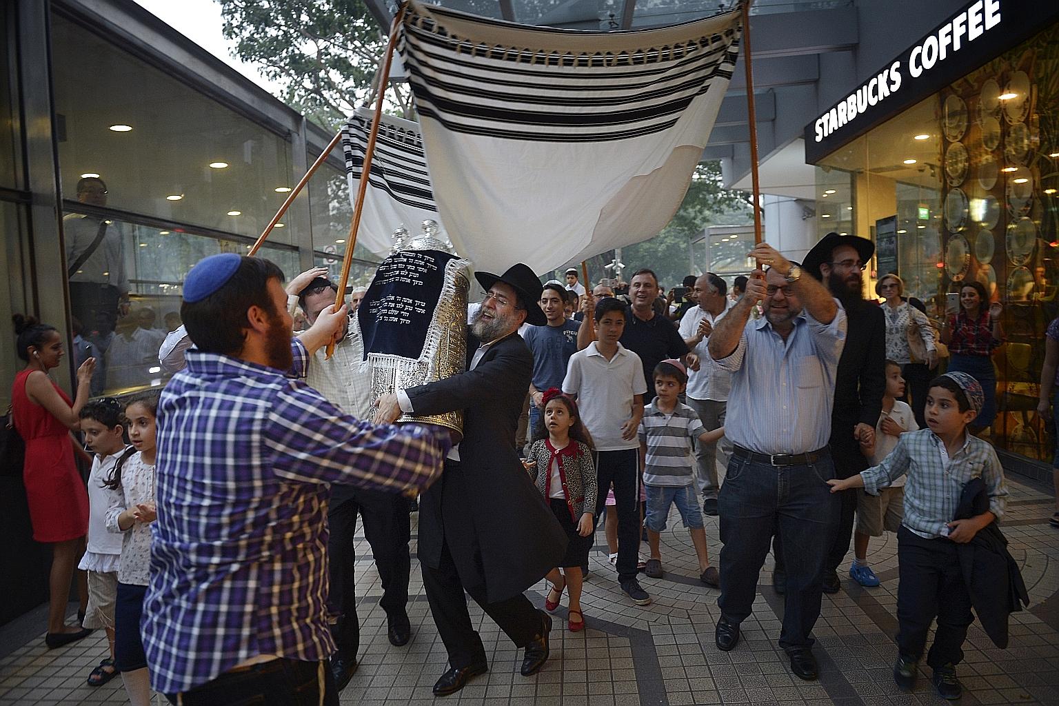 Rabbi Abergel holds a newly completed set of Torah as he and other members of the Jewish community celebrate on the streets outside the Maghain Aboth Synagogue. The joyous event usually concludes with a festive meal.