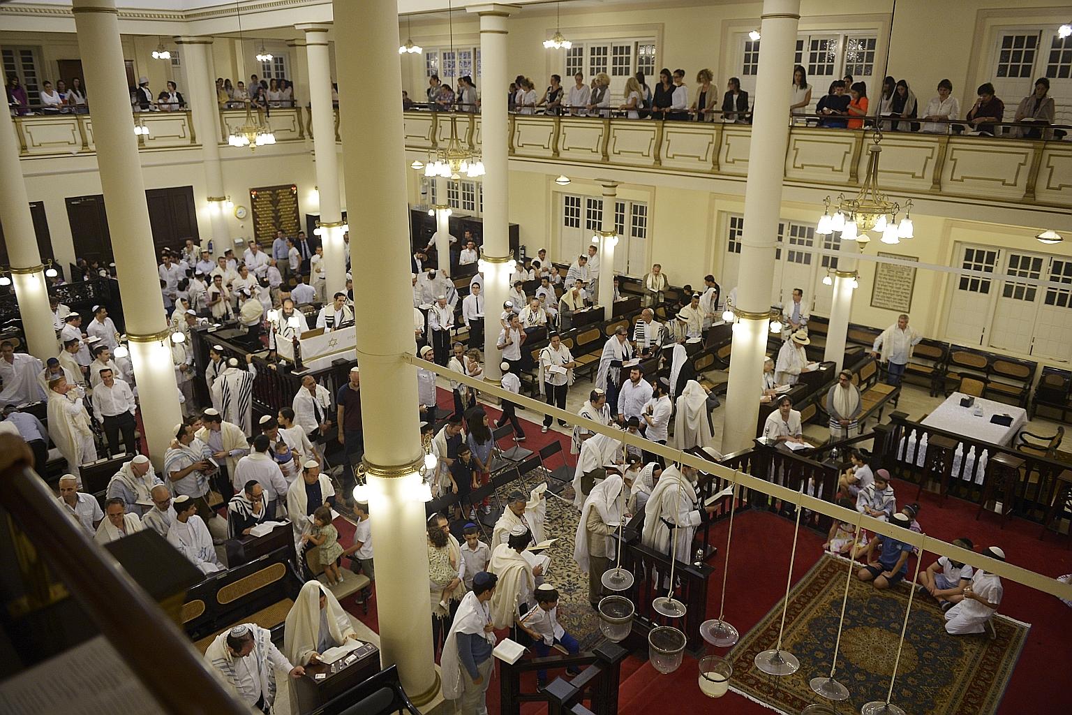 The Jewish community (above) prays inside the Maghain Aboth Synagogue after the end of the fasting period.