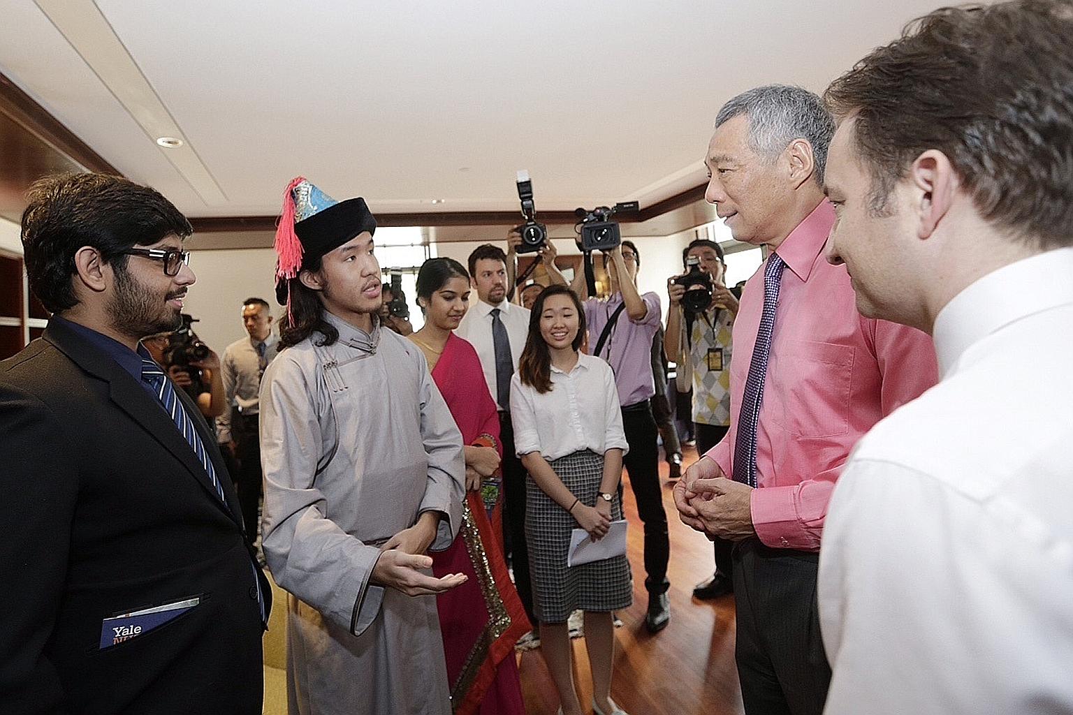 Prime Minister Lee Hsien Loong speaking with students, some in their ethnic costumes, at the inauguration of the college campus yesterday, as Yale-NUS founding president Pericles Lewis (far right) looked on. Mr Lee says the college needs a curriculum