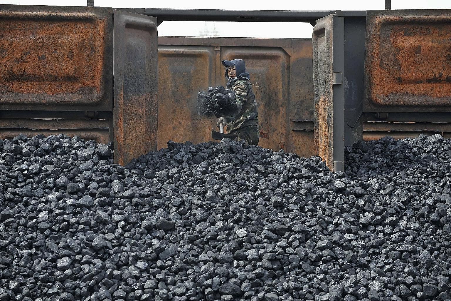 A worker unloading coal at a storage site along a railway station in Shenyang, Liaoning province, in China. Faced with choking air pollution, China is starting to shift away from coal-fired power plants and is also forcing dirty industries to clean u