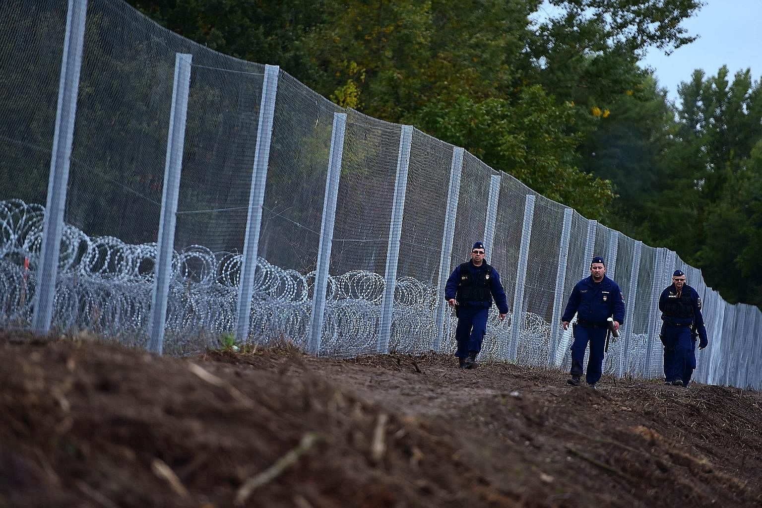 Police officers patrolling a newly erected fence at the Hungarian- Croatian border near Zakany. As governments erect barriers and reinstate border controls, the refugee crisis is disrupting flows of people and gumming up trade.