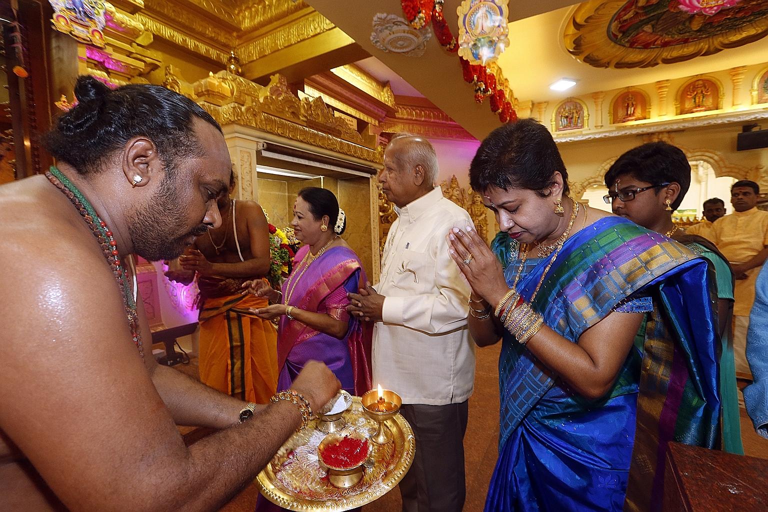 Mrs Parvathi Rajesh, CEO of Sree Maha Mariamman Temple, receiving blessings from a priest on Deepavali yesterday. She was there for morning prayers with her family (behind from right) - daughter Vaishnavi Kalyani, father Ramasamy Varadan and mother K