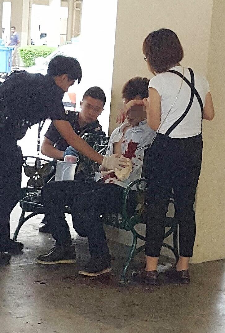 Policemen attending to the victim as the attacker's wife helps them after a stabbing incident at Woodlands Avenue 6.