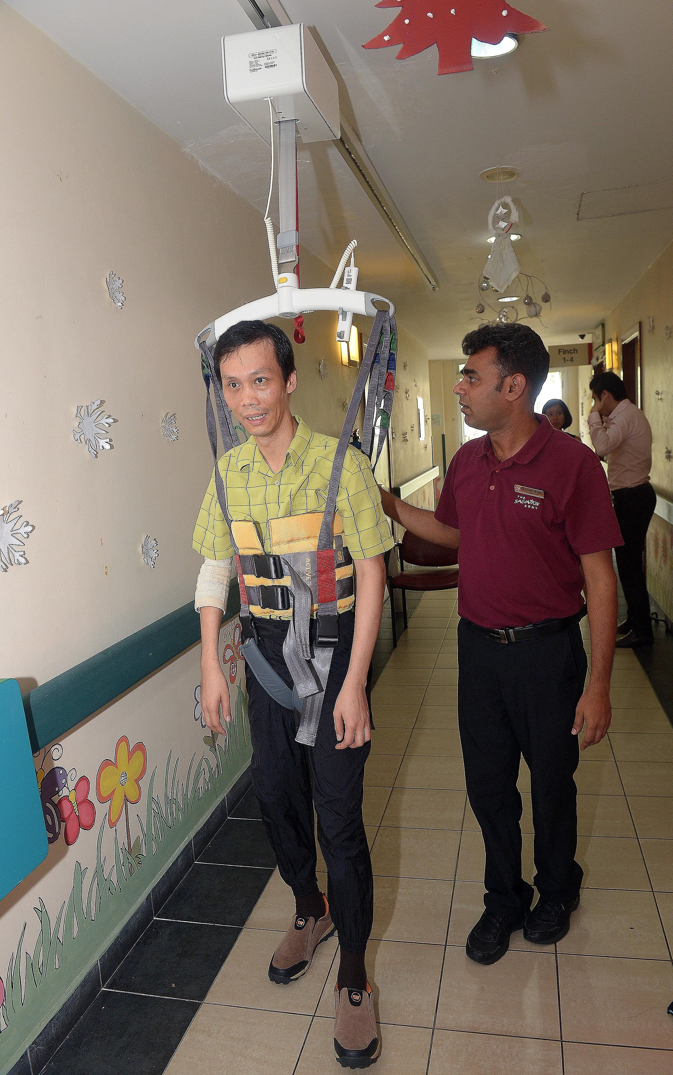 Senior physiotherapist Gladwin Prabhu, 39, helping along client Chang Phan Yong, 41, who is strapped into a newly installed ceiling hoist at The Salvation Army's Peacehaven Nursing Home, yesterday. Funds for the $10,000 hoist were donated by Nippon P