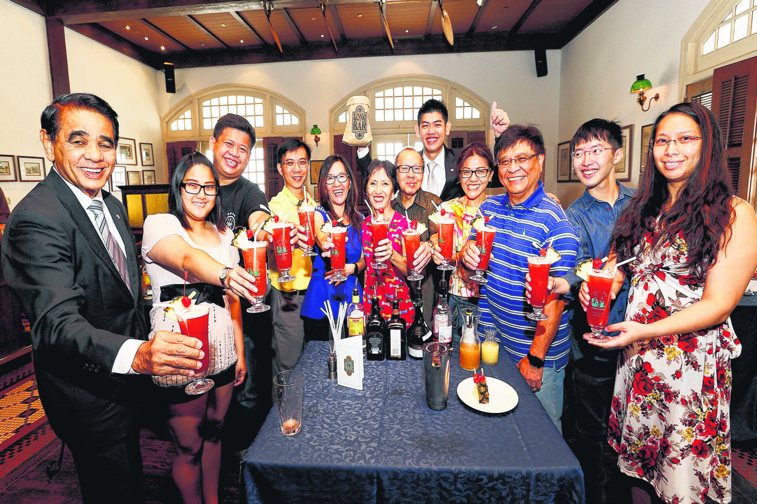 Raising a toast with their Singapore Slings in the Raffles Hotel Long Bar are (from left) Raffles Hotel resident historian Leslie Danker, 76; Ms Eunicia Tan, 22; Mr Gibson Chua, 25; Mr Gary Tan, 51; Ms Elin Loo, 49; Ms Irene Tan, 58; Mr Patrick Tan,
