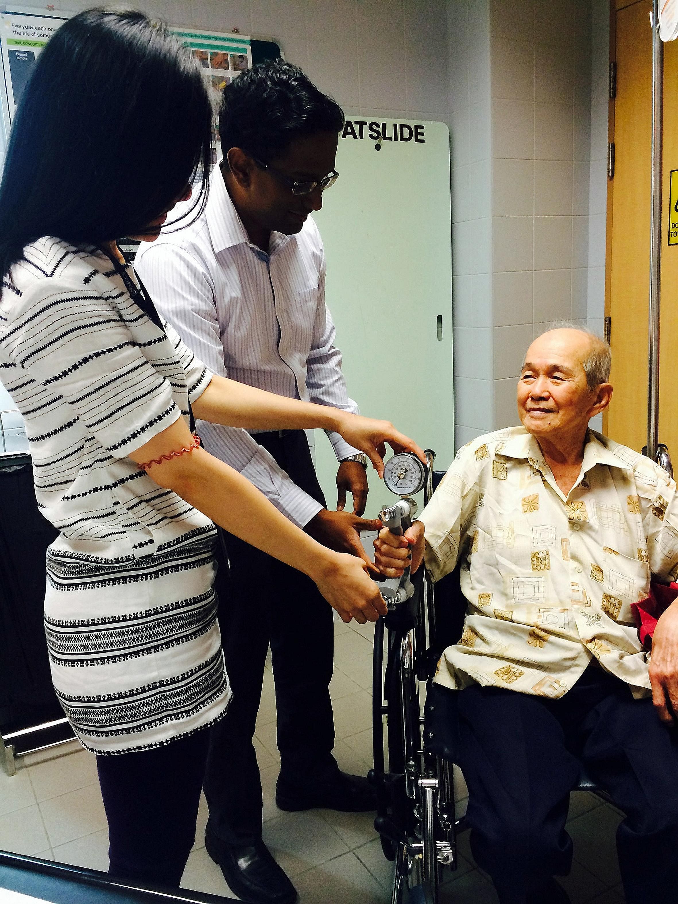 Dr Ravindran Kanesvaran and clinical coordinator Ong Zi Ling testing an elderly cancer patient's grip strength at the National Cancer Centre Singapore.