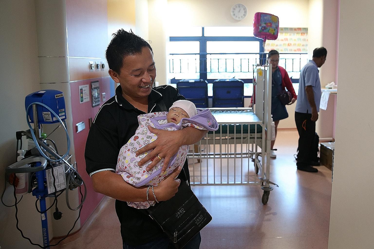 Mr Lim is all smiles as he gets his baby daughter, Jeslyn, ready to leave KKH. He and his wife took their baby home to Batam yesterday. On Dec 4, the baby underwent a seven-hour operation to remove a 25cm-wide tumour extending from her tailbone.