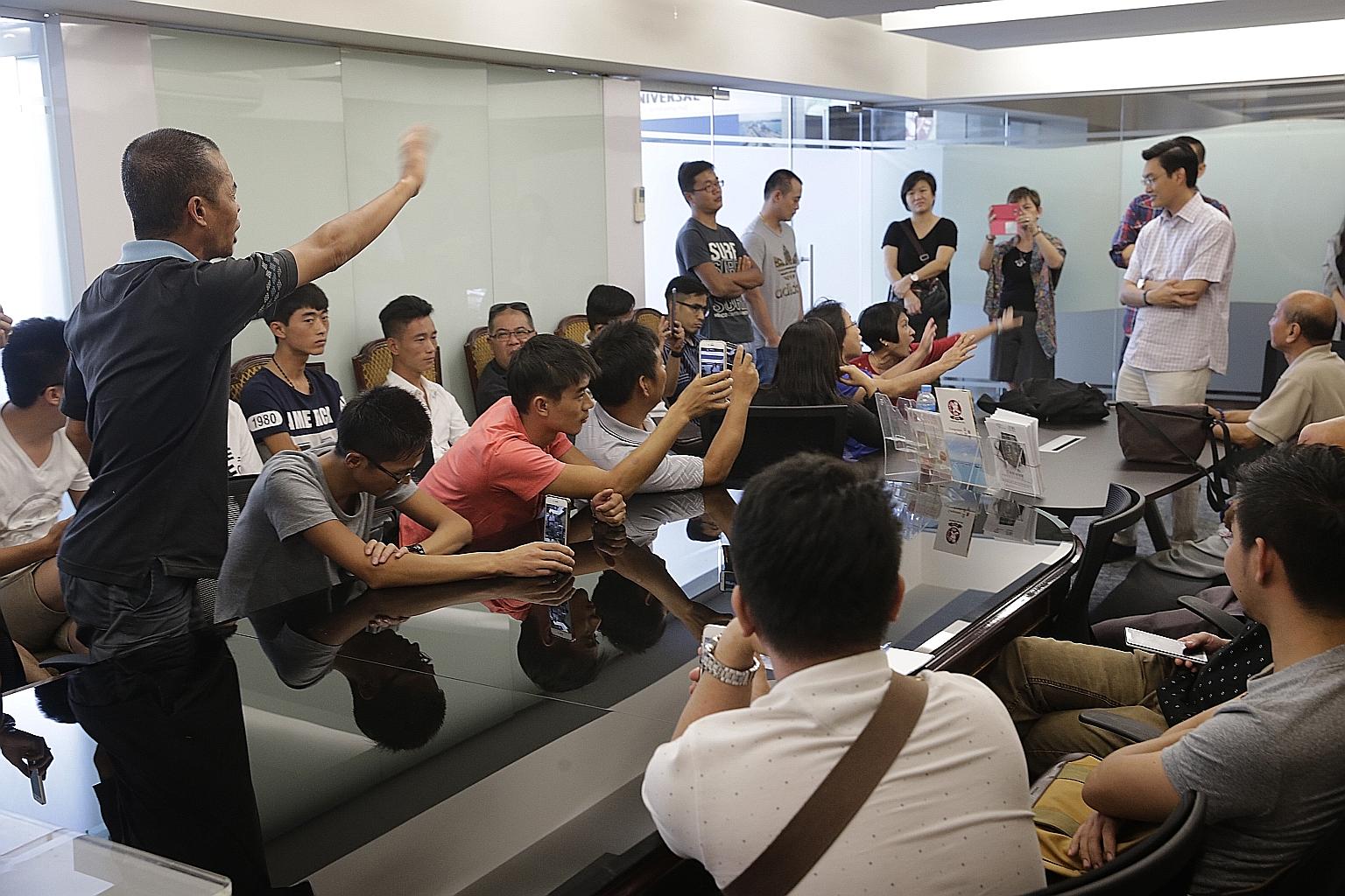 Former employees of Singapore River Explorer demanding compensation yesterday from Mr Nelson Goh (standing, in white), a director of Leisure Empire which co-owned the company with Global Yellow Pages. They were laid off when it ceased operations on D