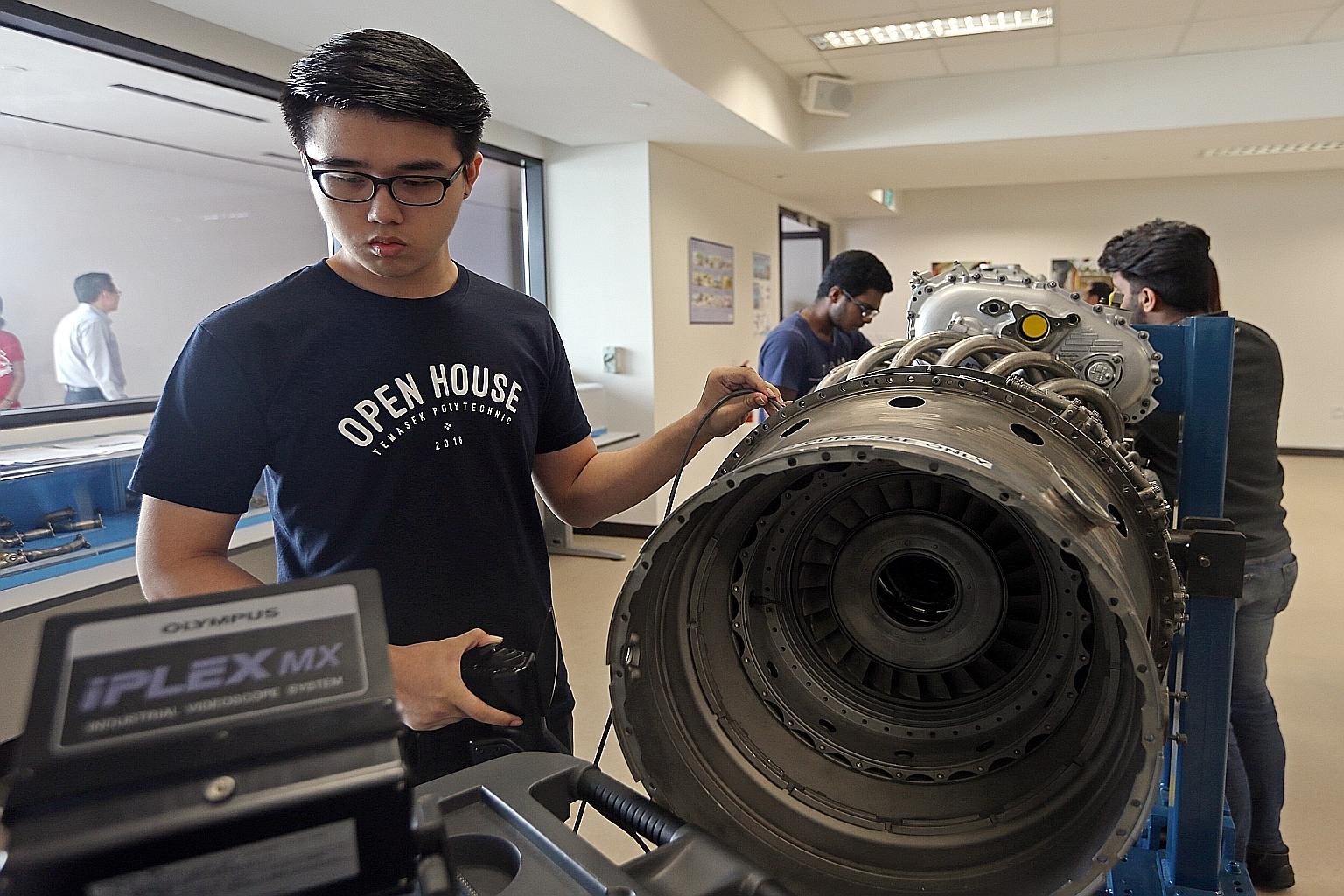 Aerospace Engineering student Poh Kiat Wei, 19, at the Engine Training Workshop during the opening of Temasek Poly's aviation academy yesterday. The academy has facilities that include an aircraft-access training hangar, a wind tunnel and flight simu