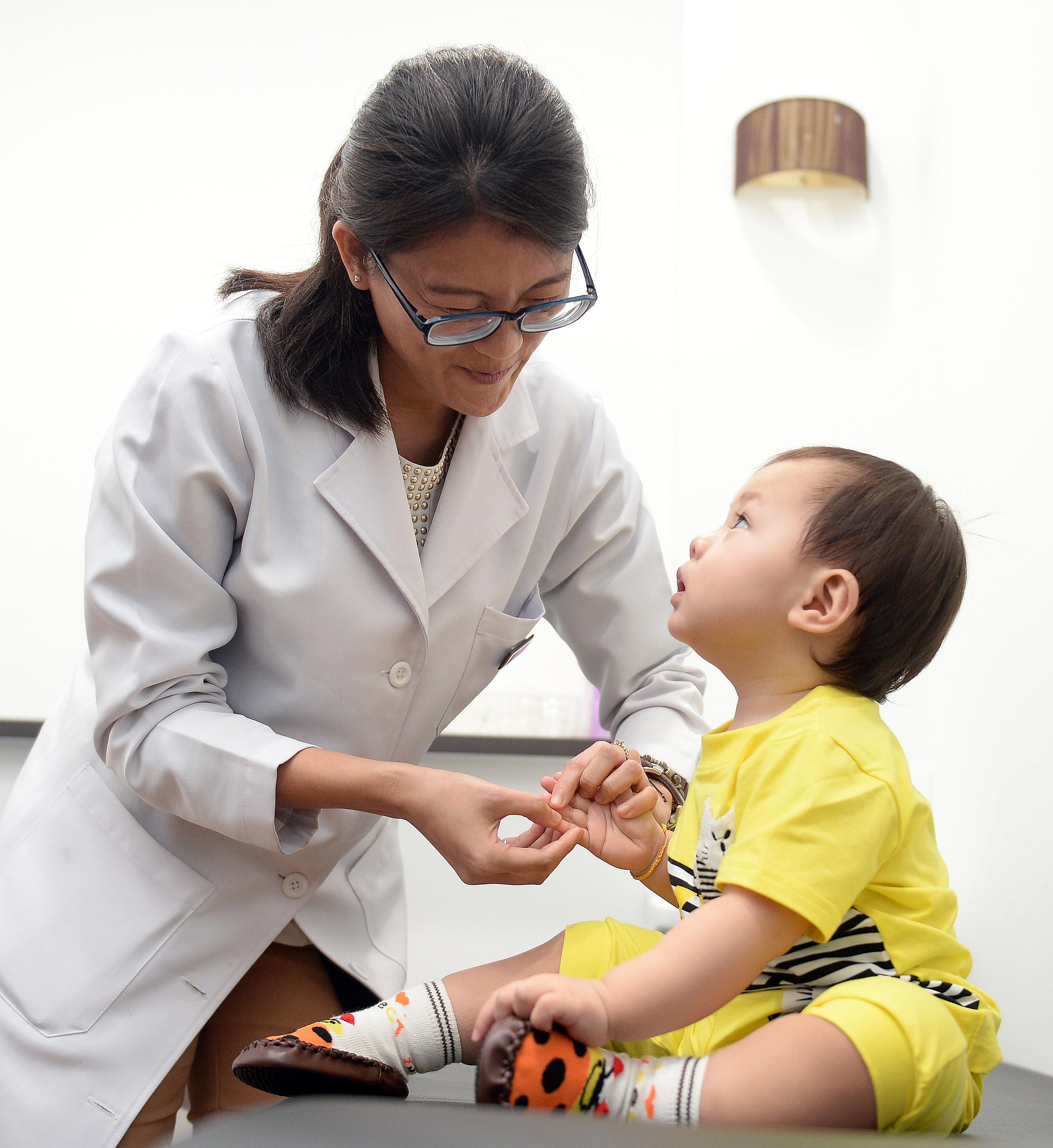 Ms Neo, Eu Yan Sang's TCM physician, showing how tuina is administered to a young patient. TCM clinics have noticed a slow but steady rise in the number of young customers over the past three or four years.