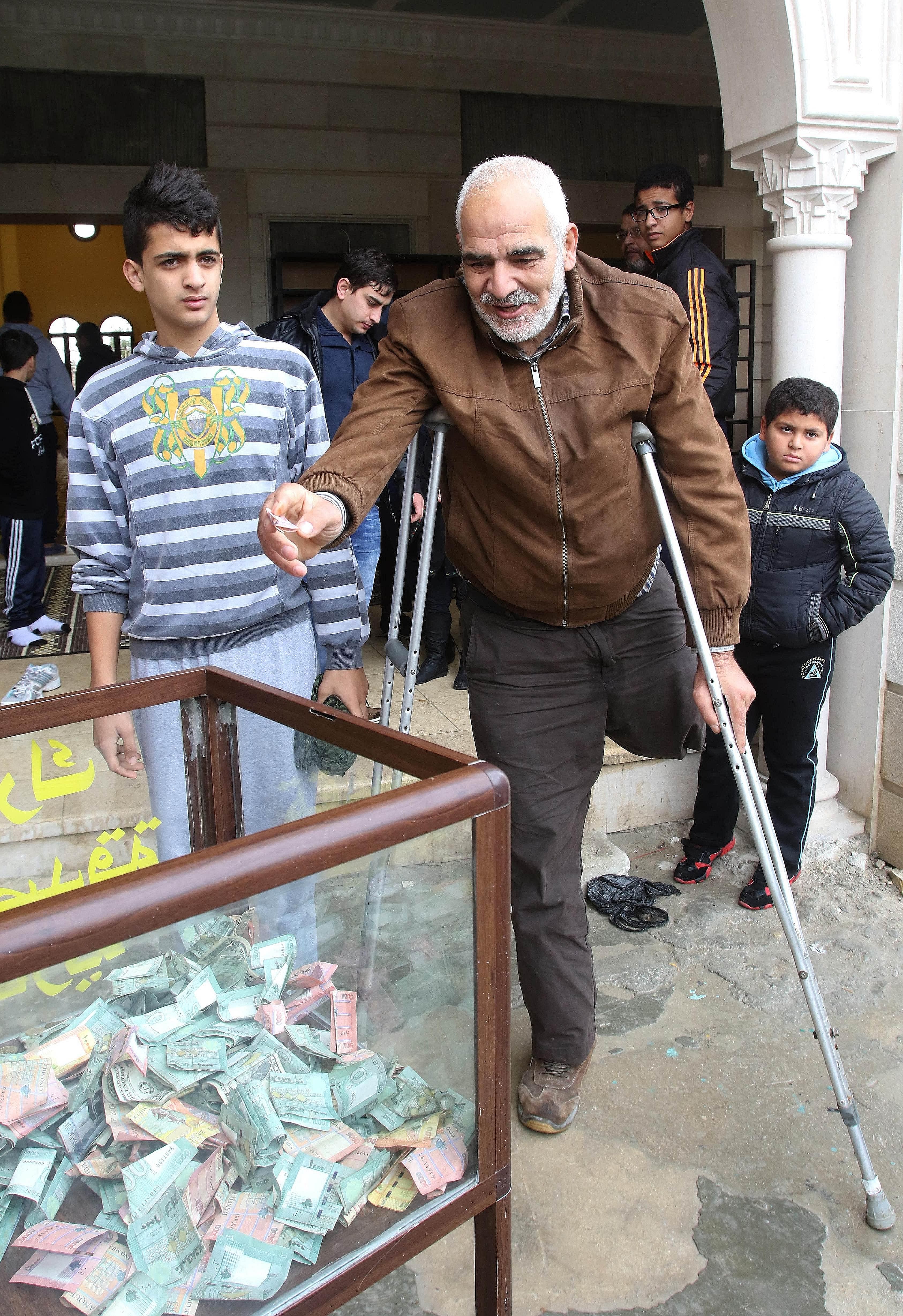 (Top) A malnourished toddler in the town of Madaya, where dozens of people have died from hunger-related causes. (Left) A Sunni man donating money for the people of Madaya as he leaves a mosque in the southern Lebanese port city of Sidon this week.