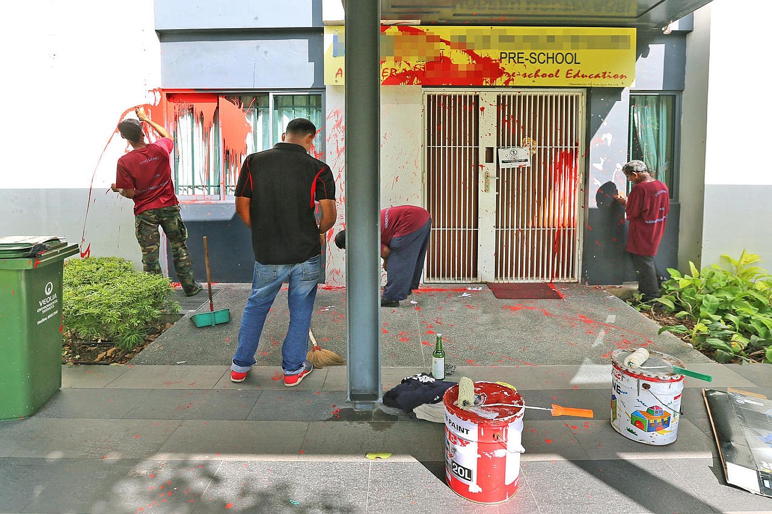 Workers attempting to scrub off the paint splashed at the Modern Montessori International at The Pinnacle@ Duxton yesterday. The incident has prompted unease among residents, one of whom said it was surprising that loan sharks would choose to target 