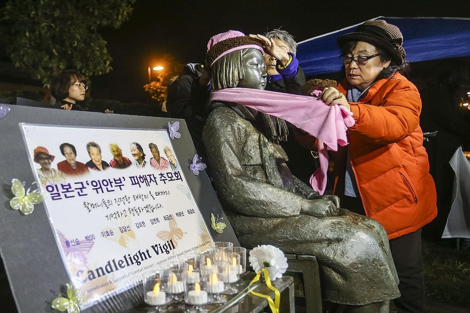 Supporters placing a scarf and a hat on a memorial statue honouring comfort women at Glendale Peace Monument in California during a candlelight vigil on Jan 5.